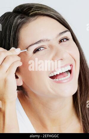 Portrait d'une jeune femme en train de toucher ses sourcils et de rire Banque D'Images