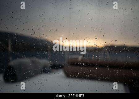 Gros plan de gouttes de pluie sur une fenêtre de navire avec un beau coucher de soleil en arrière-plan Banque D'Images