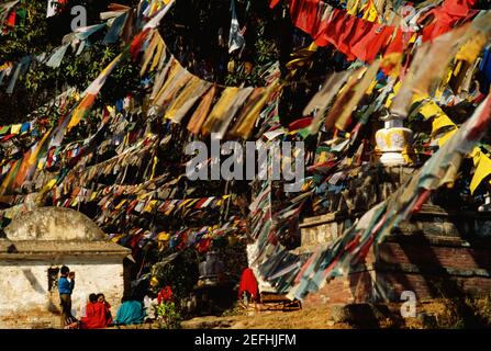 Groupe de personnes assis sous les drapeaux de prière, Temple du singe, Katmandou, Népal Banque D'Images