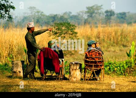 Touristes regardant à travers des jumelles avec un guide debout à côté d'eux, Tiger Tops, parc national de Chitwan, Népal Banque D'Images