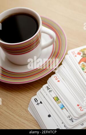 Vue en grand angle d'une tasse de thé noir avec cartes à jouer Banque D'Images