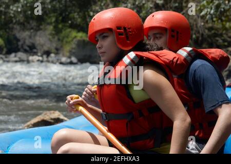 Profil d'un jeune homme et d'une jeune femme rafting dans une rivière Banque D'Images