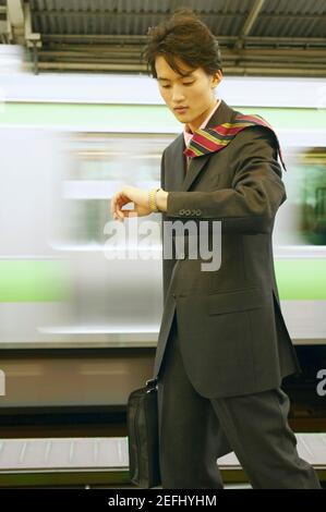 Homme d'affaires regardant sa montre-bracelet dans une station de métro Banque D'Images