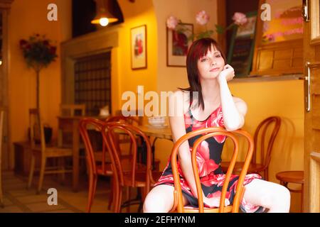 Jeune femme assise sur une chaise avec sa main son menton Banque D'Images