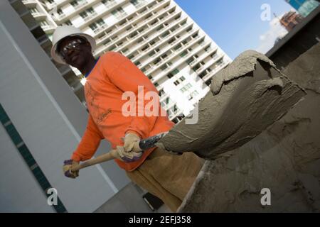 Vue à angle bas d'un ouvrier de la construction de pelles de ciment Banque D'Images