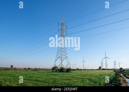 Pôle électrique haute tension avec ferme de riz vert dans la journée heure Banque D'Images