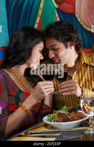 Portrait of a young couple toasting with wine dans un restaurant Banque D'Images