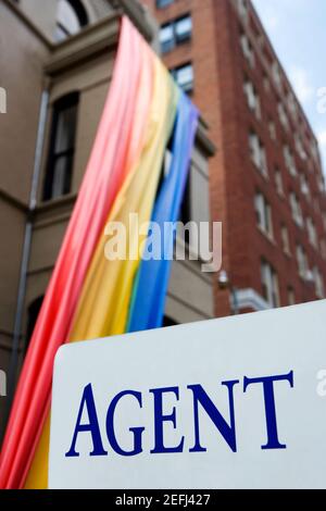 Panneau devant un drapeau arc-en-ciel suspendu à un bâtiment Banque D'Images