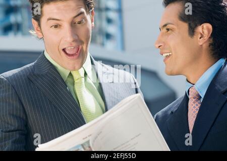 Homme d'affaires regardant un rapport boursier avec un autre homme d'affaires debout à côté de lui et souriant Banque D'Images