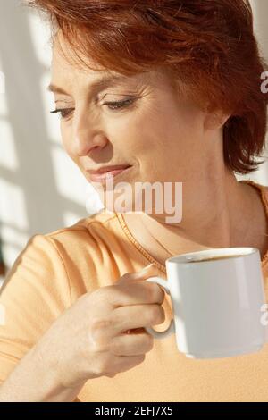 Gros plan d'une femme âgée tenant une tasse de café Banque D'Images