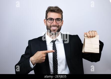 Jeune homme d'affaires portant un costume tenant et pointant un papier sac Banque D'Images