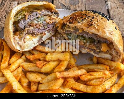 hamburger et frites coupés en deux sur l'assiette sur le bois tableau Banque D'Images