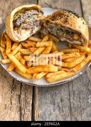 hamburger et frites coupés en deux sur l'assiette sur le bois tableau Banque D'Images