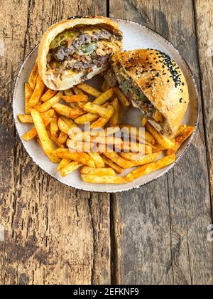 hamburger et frites coupés en deux sur l'assiette sur le bois tableau Banque D'Images