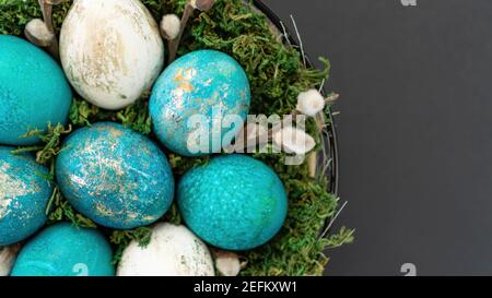 Panier de Pâques avec mousse verte et œufs peints en or et turquoise, isolé sur fond noir. Concept moderne de pâques dans le style loft. Easte Banque D'Images