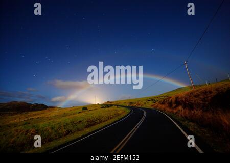 Double Moonbow apparaît au-dessus de la route du haut plateau à la lune nuit Hawaii USA. Banque D'Images