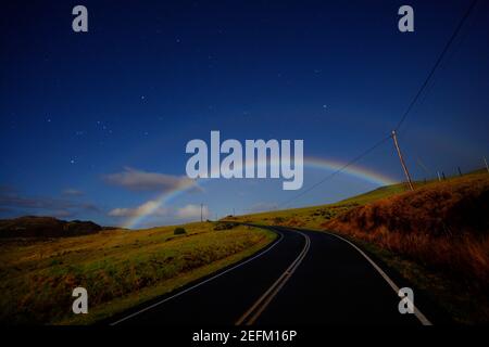 Double Moonbow apparaît au-dessus de la route du haut plateau à la lune nuit Hawaii USA. Banque D'Images