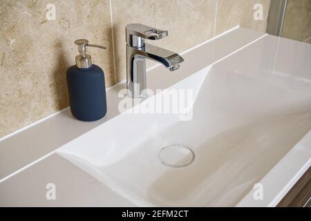 lavabo moderne avec robinet en argent, à côté d'un distributeur de savon Banque D'Images