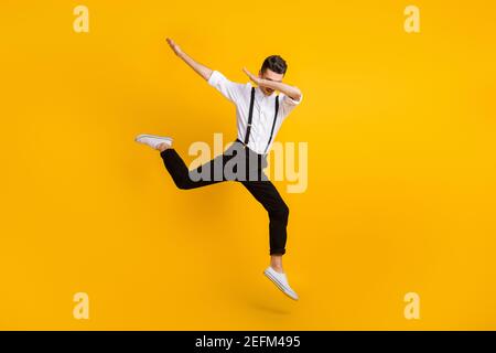 Photo de la taille du corps de l'homme qui saute dansant le hip-hop affichage du signe hype dab isolé sur fond jaune vif Banque D'Images