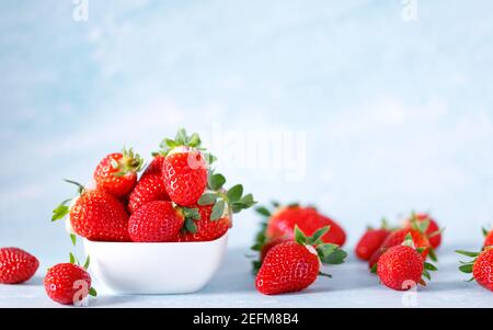 Fraises biologiques rouges crues dans un bouquet sur fond bleu. Banque D'Images