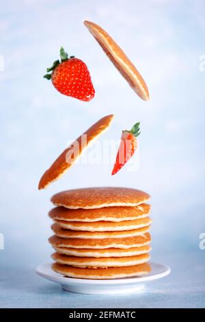 Assiette de crêpes américaines avec ingrédients volants, crêpes, fraises. Concept de nourriture saine avec espace de copie. Banque D'Images