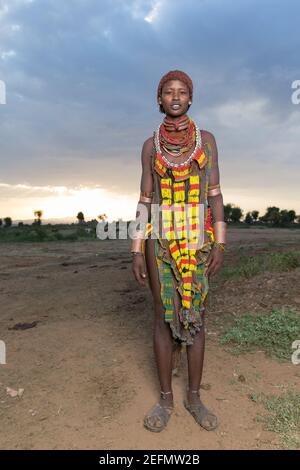 Femme Hamer au lever du soleil: Femme Hamer dans un champ où le bétail de la tribu se brout. Étant principalement des pasteurs, le groupe Hamer ou Hamar accorde leur c Banque D'Images