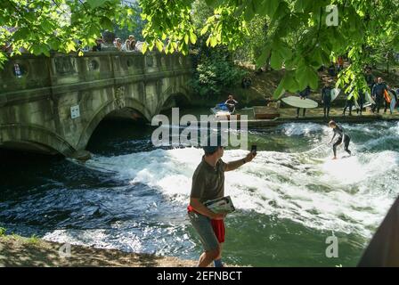 Munich, Allemagne - avril 2011 : un surfeur à cheval sur la vague d'Eisbach. Cette rivière faite par l'homme est un bras de la rivière Isar dans le parc Englischer Garten Banque D'Images