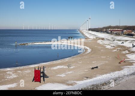 Plage hollandaise en hiver avec des éoliennes en rangée le long de la côte Banque D'Images