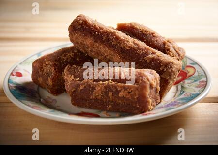 Panela tranches dans une petite assiette sur table en bois. Aussi connu sous le nom de rapadura, il est sucre de canne entier non raffiné typique de l'Amérique centrale et latine. Banque D'Images