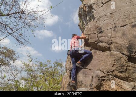 Photo d'un jeune homme grimpant sur un roche avec une corde Banque D'Images