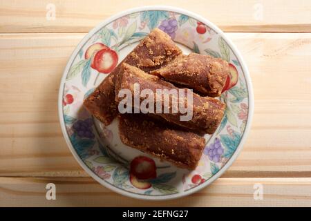 Panela tranches dans une petite assiette sur table en bois. Aussi connu sous le nom de rapadura, il est sucre de canne entier non raffiné typique de l'Amérique centrale et latine. Banque D'Images