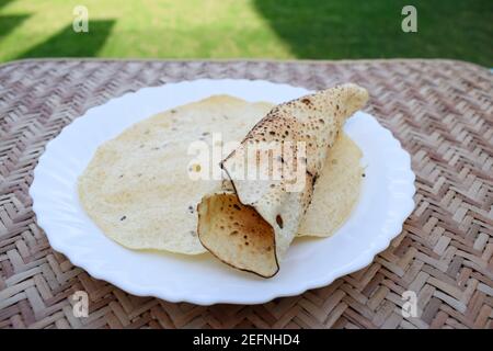 En-cas indien savoureux très apprécié, mangé avec déjeuner et dîner ou juste en-cas. Papad ou papapadoms. Papapas rôtis et frits servis dans une assiette blanche Banque D'Images