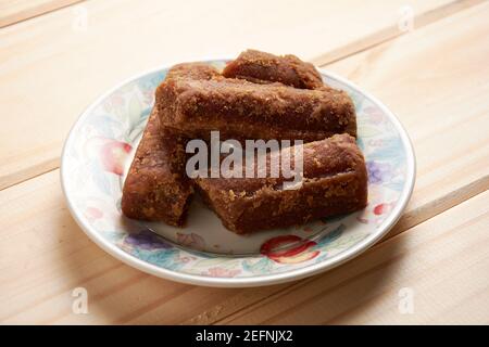 Panela tranches dans une petite assiette sur table en bois. Aussi connu sous le nom de rapadura, il est sucre de canne entier non raffiné typique de l'Amérique centrale et latine. Banque D'Images