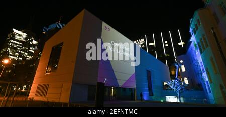 17 février 2021, Hessen, Francfort-sur-le-main: Alors que les mots « l'arbre de vie » sont projetés sur la façade du Musée juif, la sculpture sur l'arbre de la piste est baignée de lumière colorée. Le Musée juif de Francfort présentera une installation interactive de lumière et de son sur sa piste à partir du 18 février. Les projections peuvent être vues quotidiennement entre 7 et 10 heures autour de la sculpture créée spécialement pour la place, intitulée 'United', qui se compose de deux arbres en fonte d'aluminium, dont l'un atteint dans le ciel avec ses racines. Photo: Arne Dedert/dpa Banque D'Images