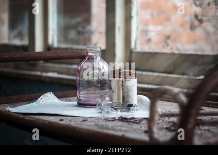 Les anciens flacons de médicaments rouges distribués et les seringues étaient en place sur un chariot métallique dans un vieux hôpital abandonné et créepy sans lumière brillante pour les patients Banque D'Images