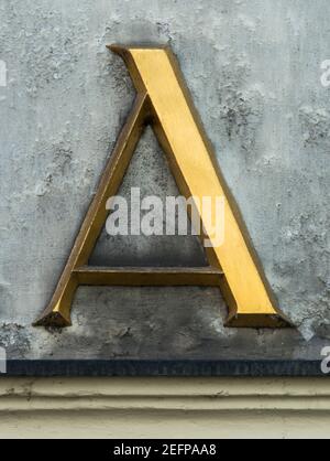 Lettre d'or A avec serifs sur un mur gris Banque D'Images