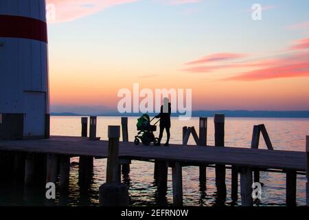 Jetée de phare avec poussette de marche silhouette de femme sur le magnifique coucher de soleil ciel fond sur le lac, phare de Podersdorf, Neusiedl See en Autriche Banque D'Images