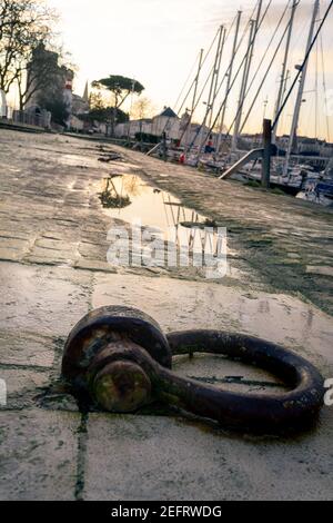 Gros plan d'un anneau d'amarrage dans le vieux port de la Rochelle. Les bâtiments et les bateaux en arrière-plan sont flous. Banque D'Images