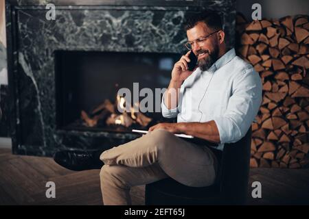 Jeune homme d'affaires souriant assis dans le salon d'un bureau et parler avec un client par téléphone Banque D'Images