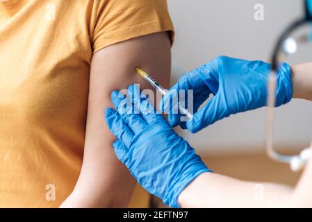 Gros plan des mains du médecin portant des gants de protection donnant une dose de vaccin à un patient en laboratoire. Vaccination contre l'infection à coronavirus Covid 19, une infirmière injectant le vaccin dans un bras de Banque D'Images