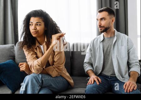 Un couple marié découvre la relation, une querelle entre les amoureux. Couple multiracial dans l'amour se querelant à la maison sur le canapé pour des problèmes de ménage ou de finances. Concept de conflits familiaux domestiques Banque D'Images