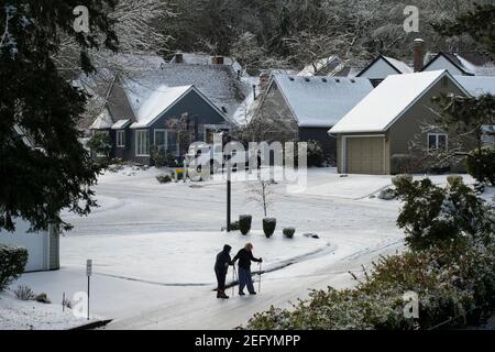 Un couple senior se promeuve sur la route glacée avec prudence au lac Oswego, Oregon, le 15 février 2021, après que la neige et la pluie verglaçante ont frappé la zone métropolitaine de Portland. Banque D'Images