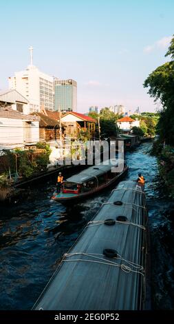 Deux bateaux khlong passent l'un à côté de l'autre dans le canal étroit de Bangkok, en Thaïlande. Banque D'Images