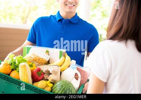 Liveur livrant de la nourriture à une femme à la maison - concept de service d'épicerie en ligne Banque D'Images