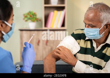 Après que le médecin donne la vaccination par injection au patient âgé par une seringue ou une injonction, le patient frottant son épaule à la maison - concept de contrôle de santé à la maison Banque D'Images