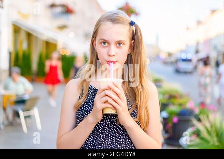 portrait d'une adolescente tenant et buvant un milkshake à bulles cocktail acheté dans un camion de nourriture de rue dans un soleil jour d'été et regarder dans un venu Banque D'Images