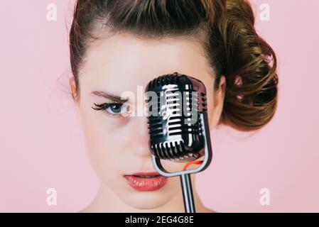 Fille dans des verres chantent dans le microphone. Beauté et mode vintage. Musique, look et style rétro. Pinup jeune fille avec microphone rétro. Fille chantent Banque D'Images