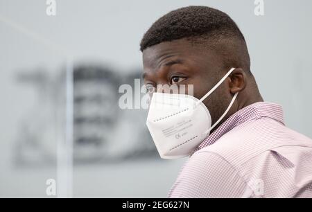 Stuttgart, Allemagne. 18 février 2021. Un réfugié du Cameroun est assis dans la salle d'audience du tribunal administratif de Stuttgart avant le début du procès. Le procès de l'homme contre l'État de Baden-Württemberg commence au tribunal administratif de Stuttgart. Sa plainte est contre ce qu'il considère être une action disproportionnée de la police lors d'une opération au centre d'accueil initial (LEA) à Ellwangen et lors de sa déportation en 2018. Credit: Marijan Murat/dpa/Alamy Live News Banque D'Images