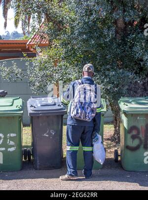 Johannesburg, Afrique du Sud - un homme noir non identifié se digue dans des poubelles résidentielles debout dans une rue de la ville Banque D'Images