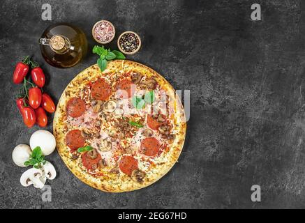 Pizza italienne chaude à Naples avec jambon et champignons à l'obscurité arrière-plan Banque D'Images